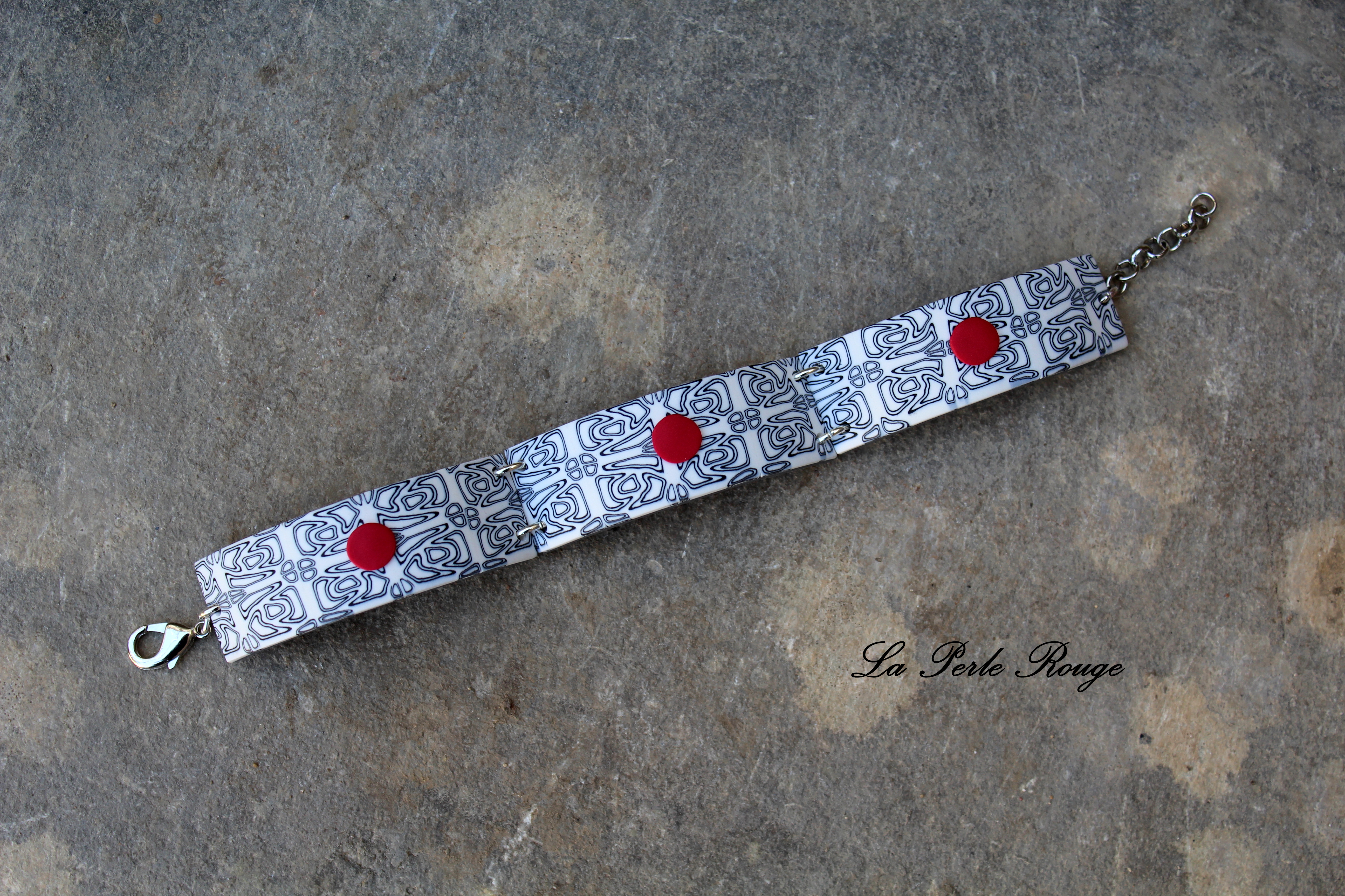 Bracelet noir et blanc et ses pitites pastilles rouges. 